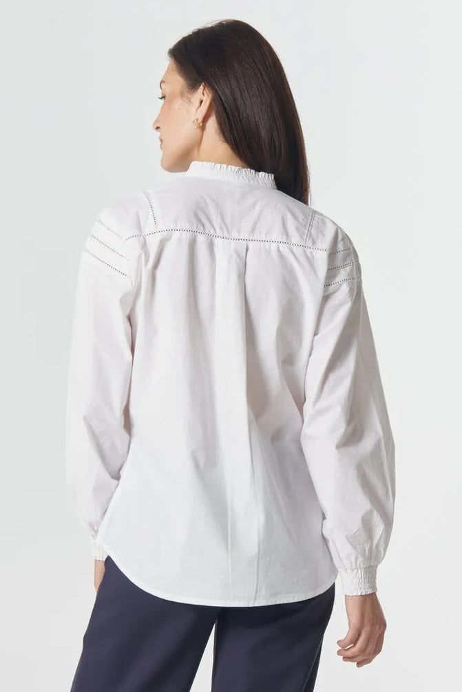 Woman wearing a white shirt and navy pants on a white background