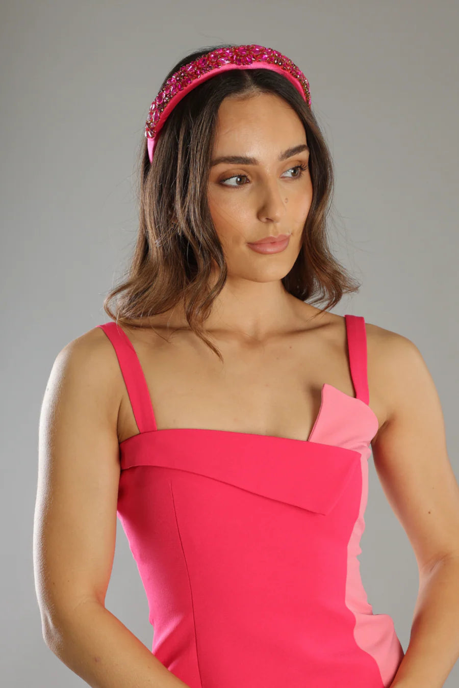 Woman wearing a pink dress and headband against a gray background