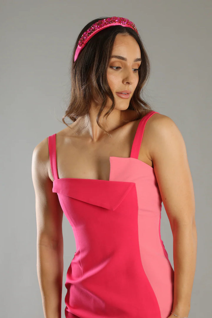 Woman wearing a pink dress with a geometric design on a gray background