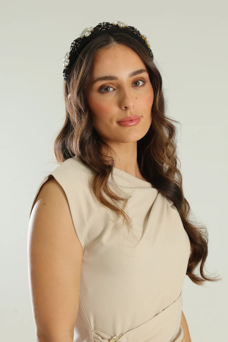Woman wearing a beige sleeveless top with a plain background