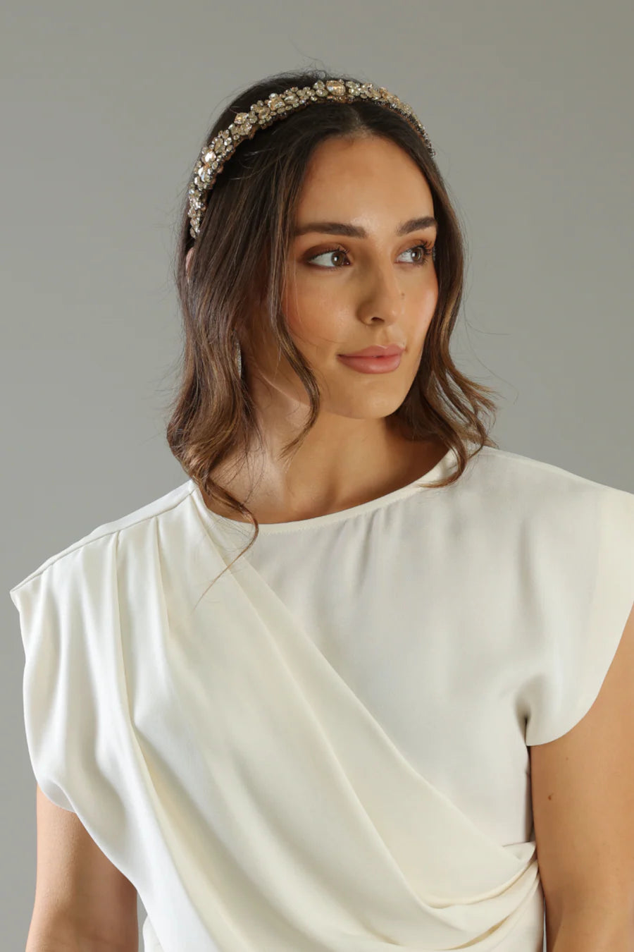 Woman wearing a white dress with a draped neckline against a gray background