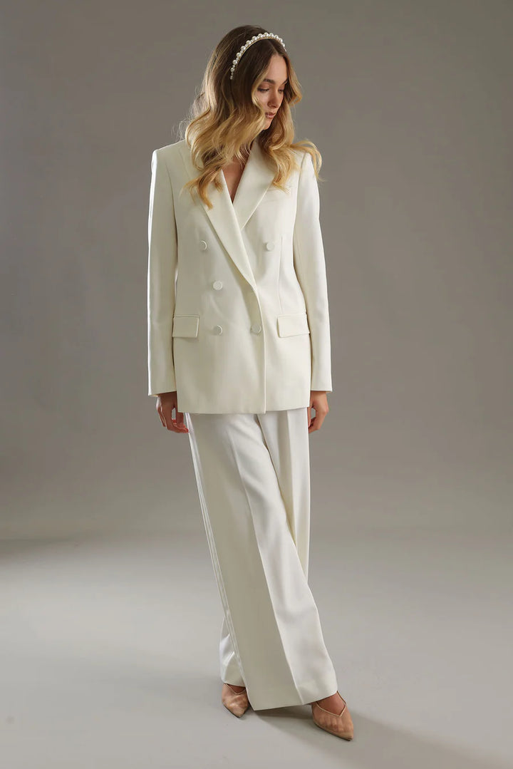 Woman wearing a white suit against a neutral background