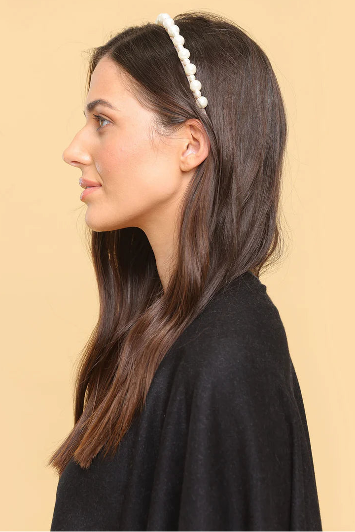 Woman wearing a pearl headband against a beige background