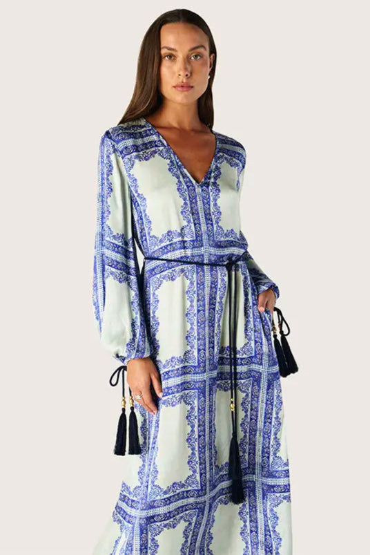 Woman wearing a blue and green patterned dress on a light gray background
