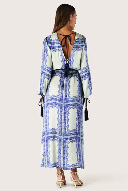 Woman wearing a blue and green patterned dress with a belt on a white background