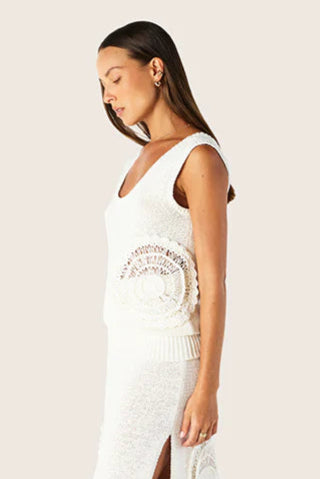 Woman wearing a white sleeveless dress with lace details on a light background