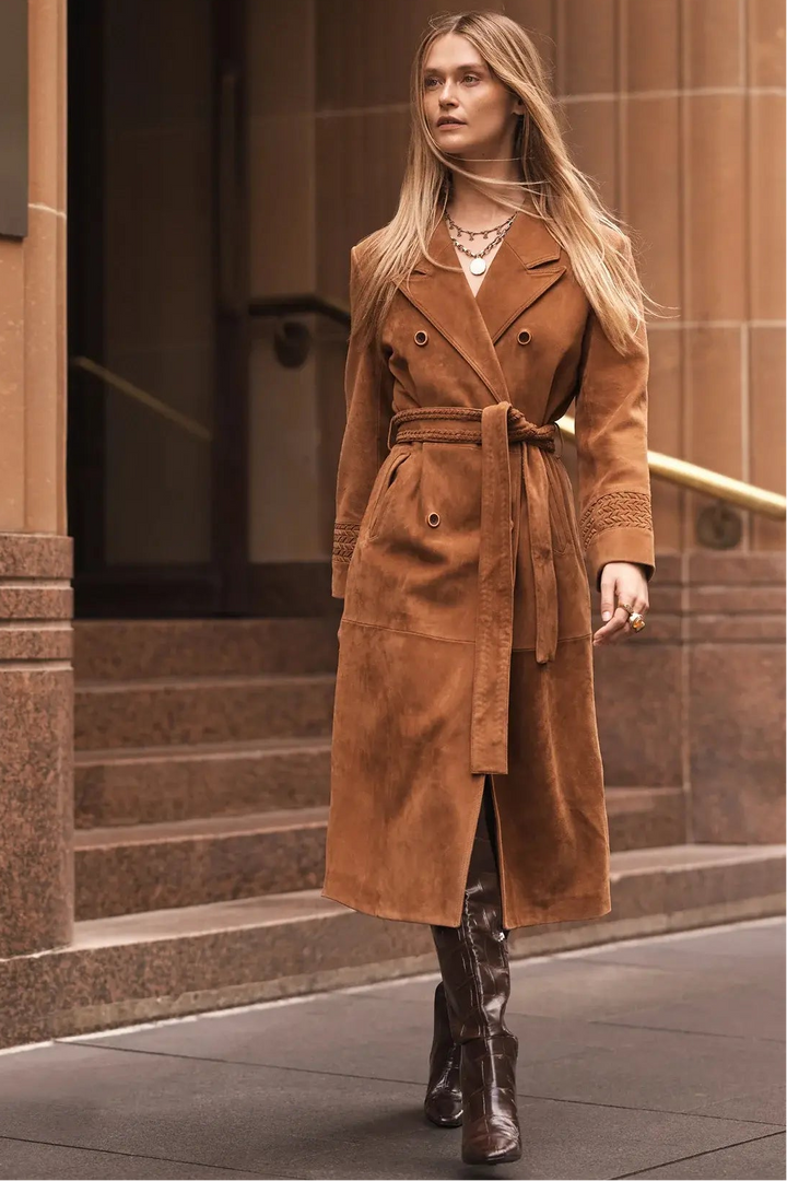 Woman wearing a brown coat standing in front of a building.