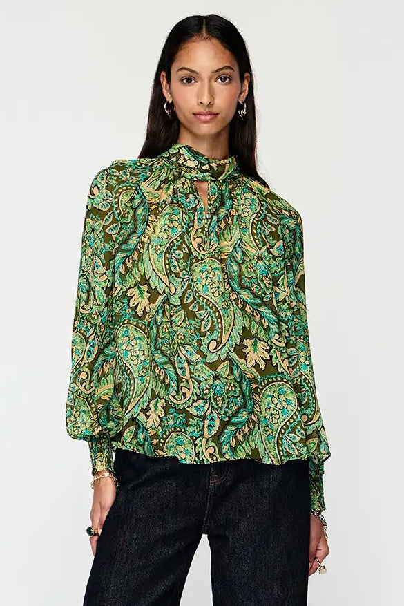 Woman wearing a green floral blouse and black pants on a white background