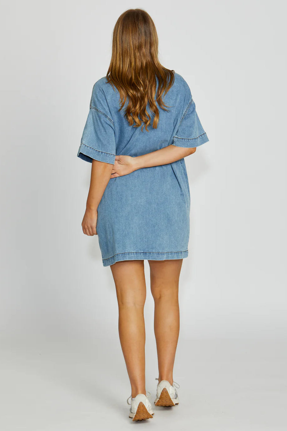Woman wearing a blue denim dress on a white background