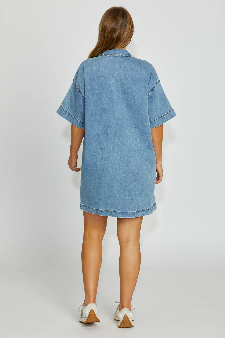 Woman wearing a blue denim dress on a white background