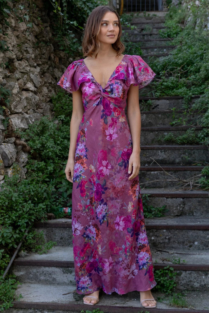 Woman in a floral dress standing on stone steps with greenery