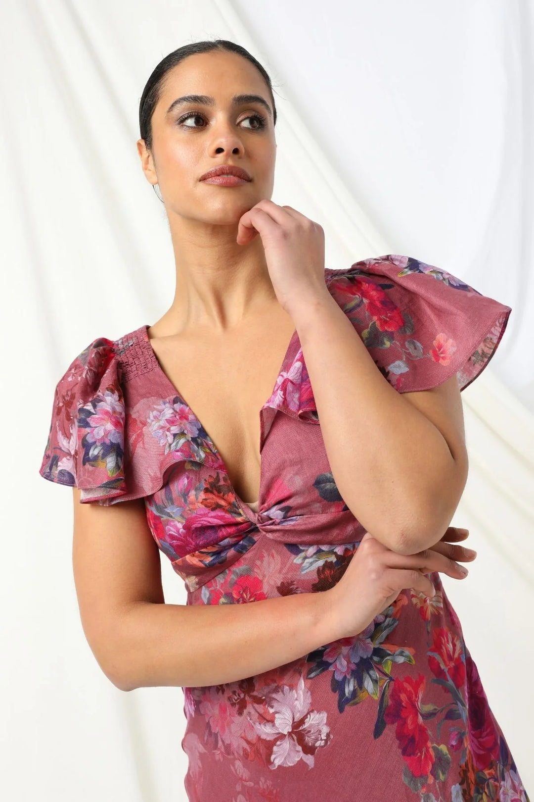 Woman wearing a floral dress with ruffled sleeves against a white background