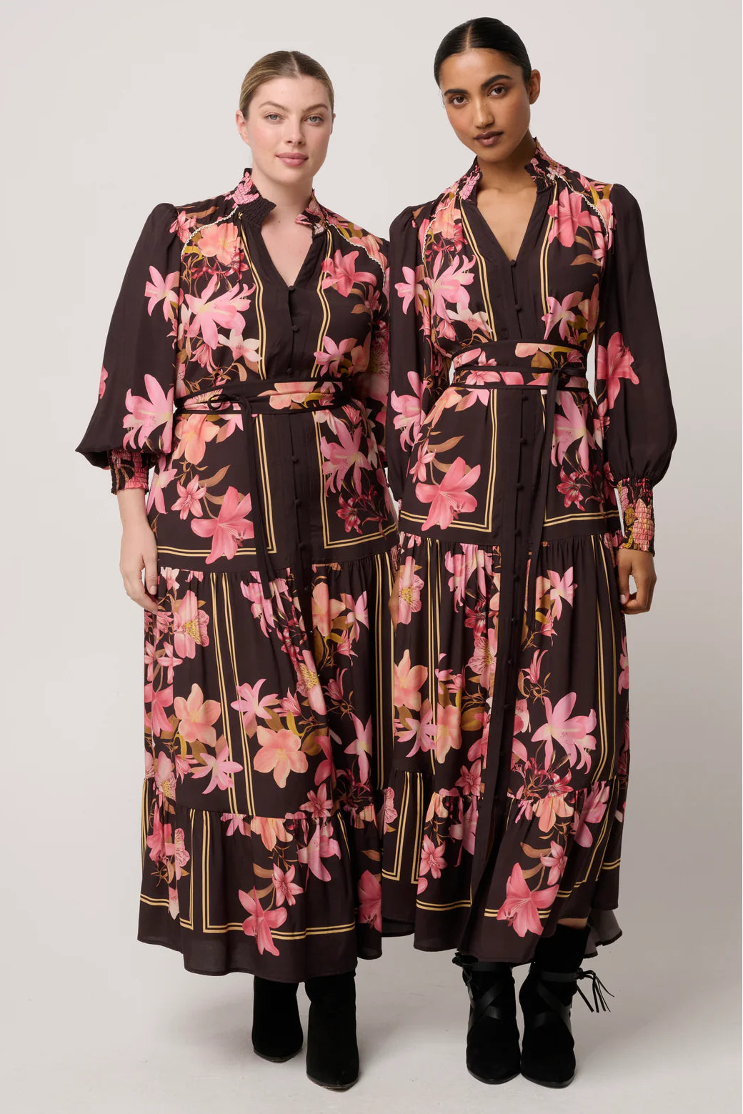 Two women wearing matching floral dresses on a white background