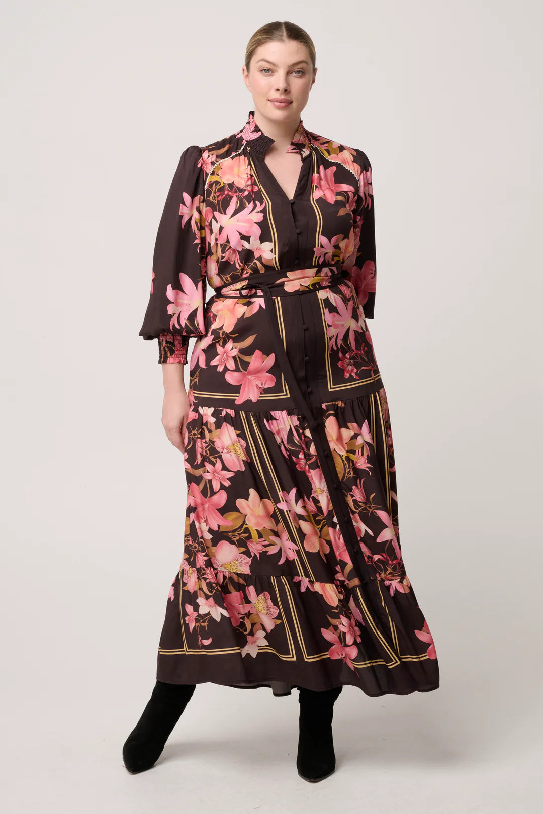 Woman wearing a black floral dress with a belt on a white background