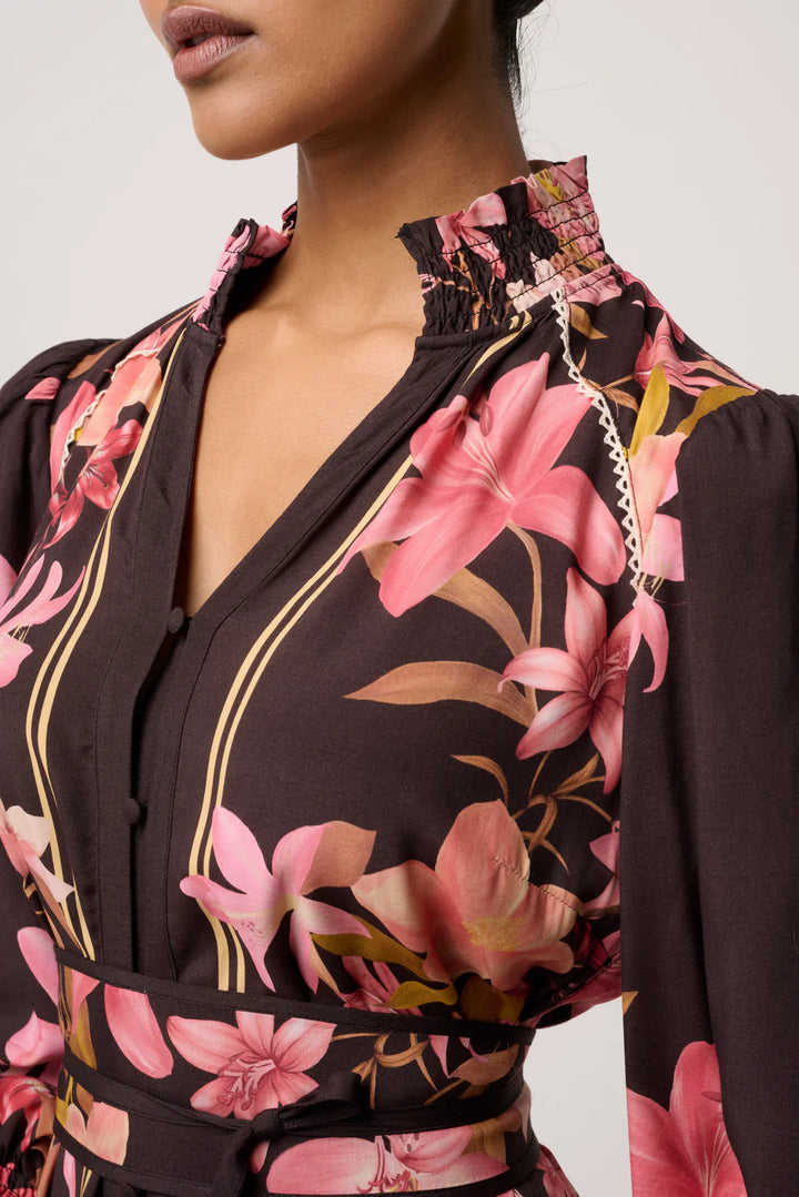 Close-up of a woman wearing a floral dress with pink flowers on a plain background