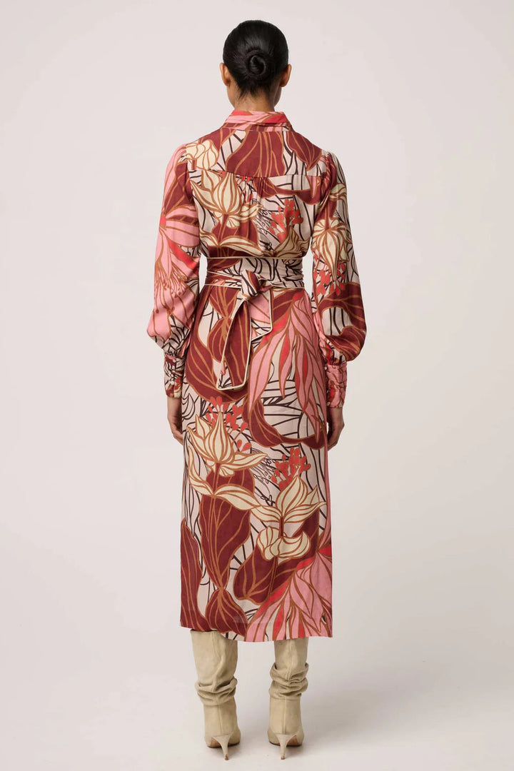 Person wearing a long, patterned dress with a belt on a white background