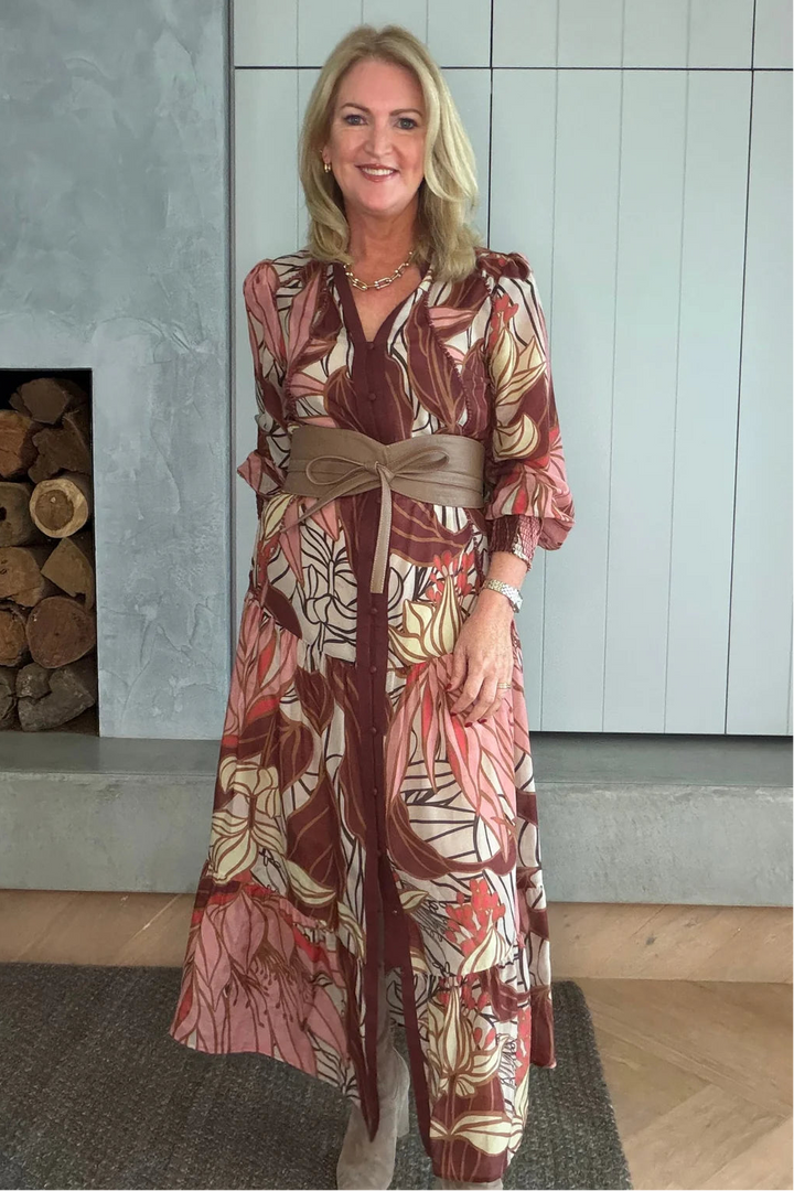 Woman wearing a patterned outfit standing in a room with a fireplace.
