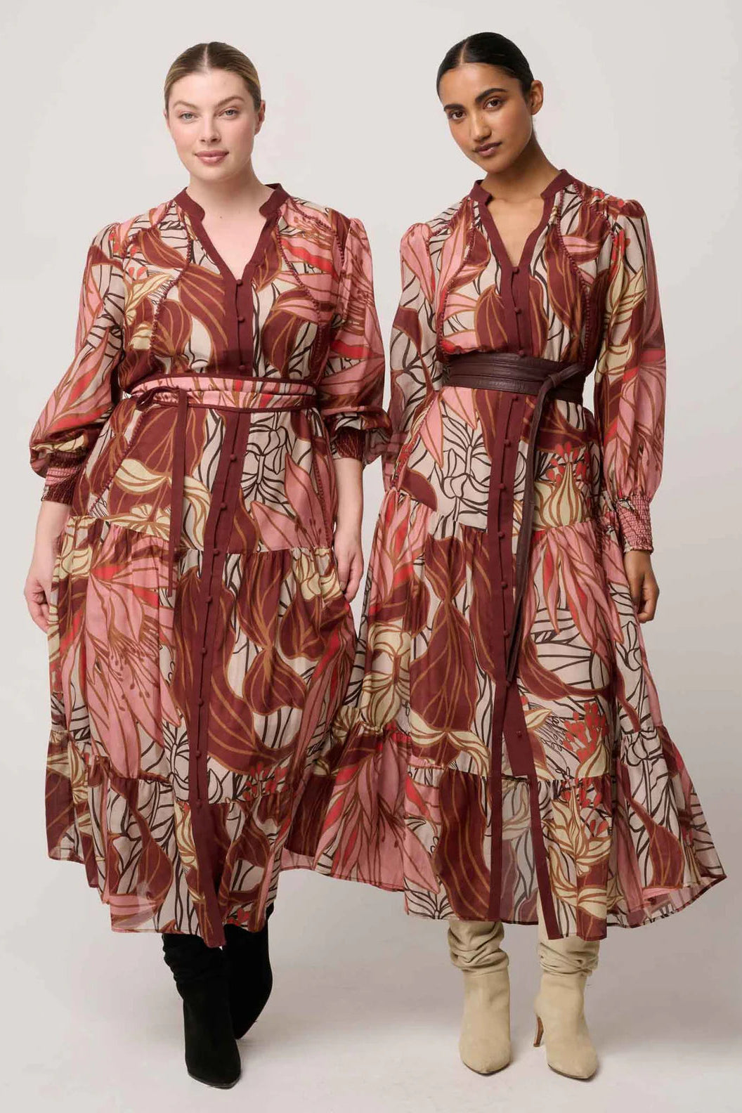 Two women wearing patterned dresses on a white background