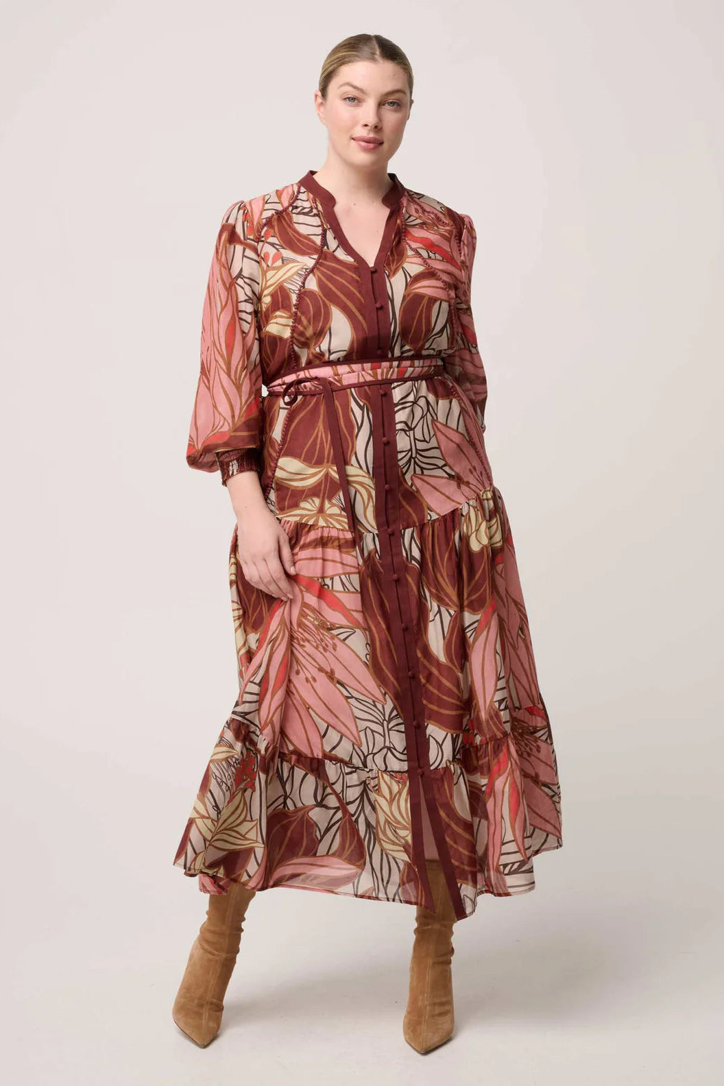 Woman wearing a patterned dress with a belt on a white background