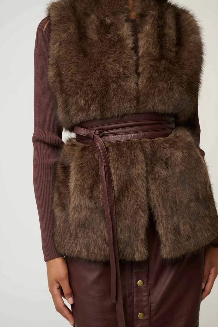 Brown fur vest with leather accents on a plain background