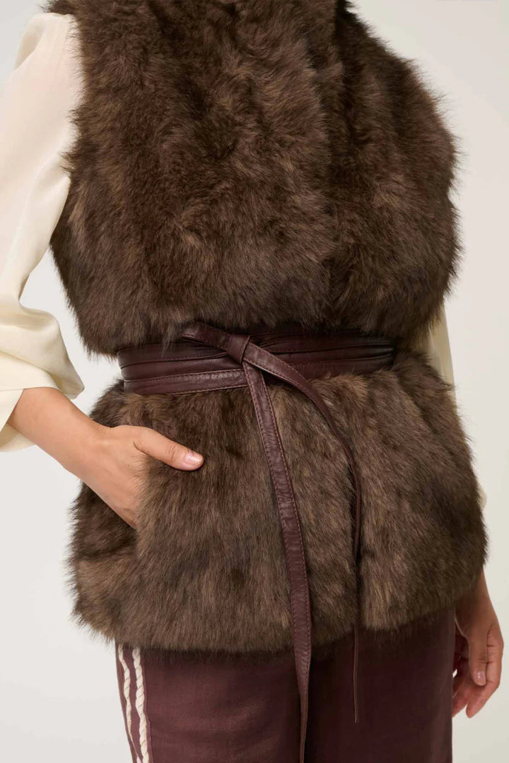 Brown fur vest worn by a person on a plain background