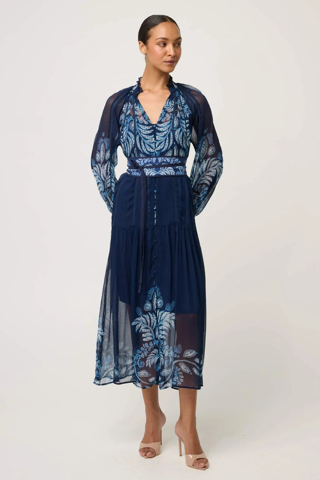 Woman wearing a navy dress with floral patterns on a white background