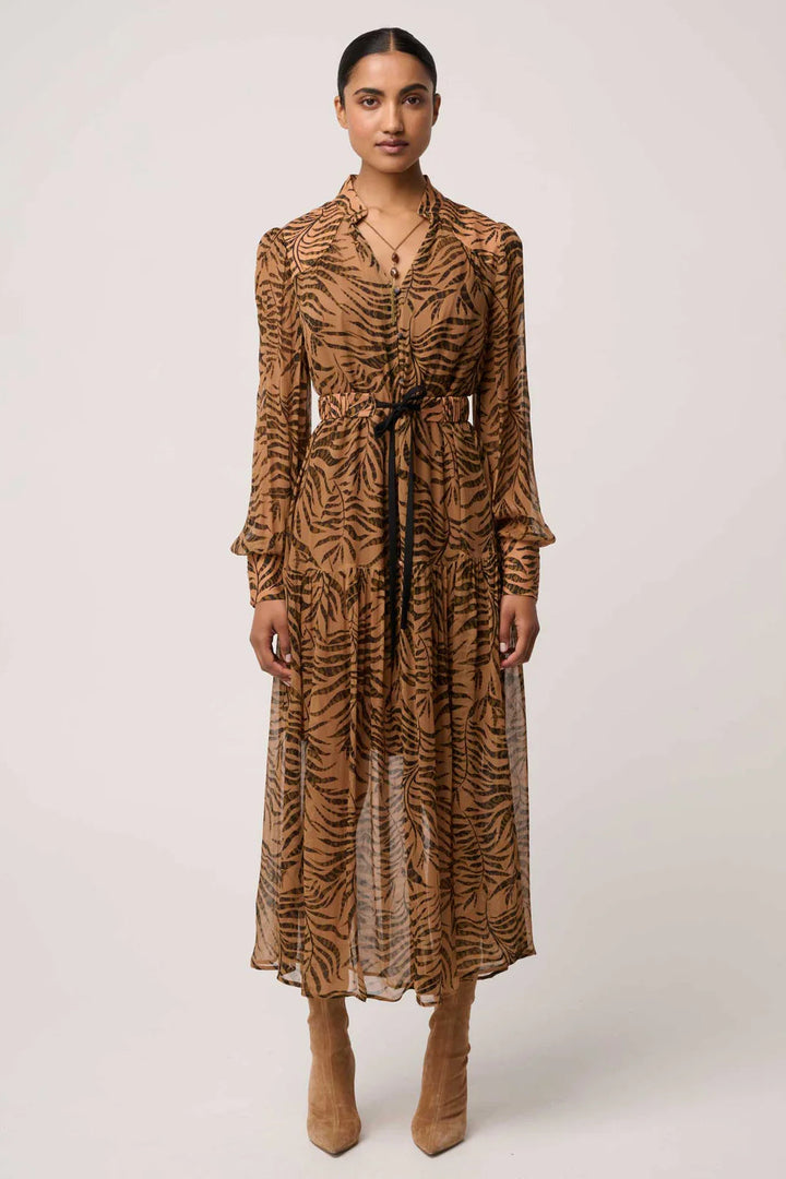 Woman wearing a long-sleeve, patterned dress with a belt on a white background