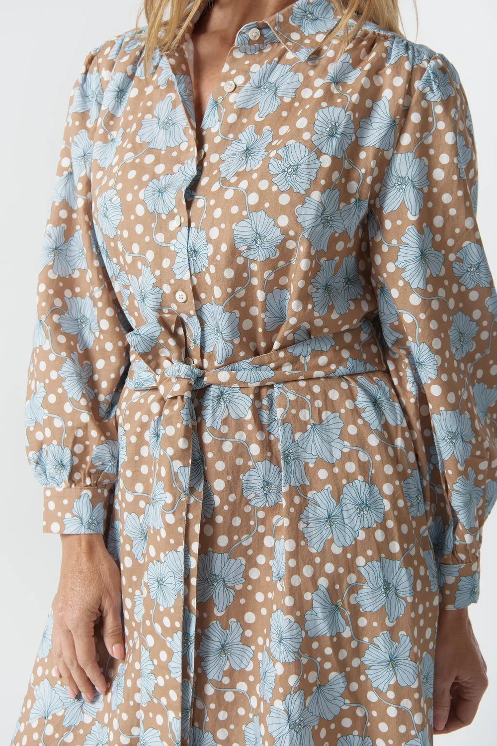 Woman wearing a floral dress with a pattern of blue flowers on a beige background