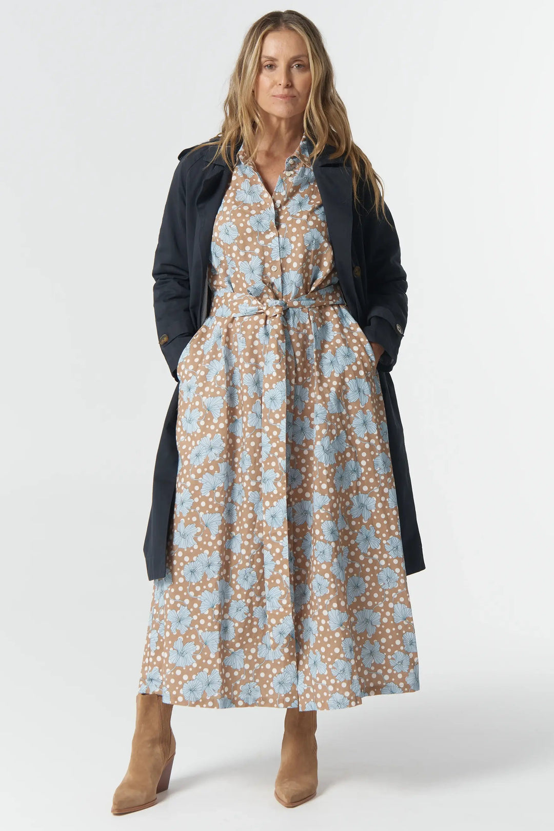 Woman wearing a floral dress with a navy cardigan on a white background
