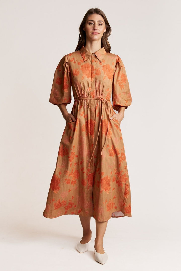 Woman wearing an orange floral dress on a white background