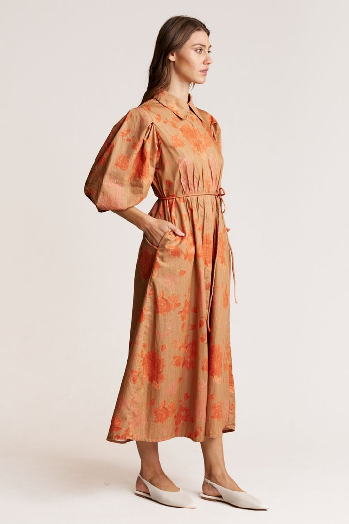 Woman wearing an orange floral dress on a white background