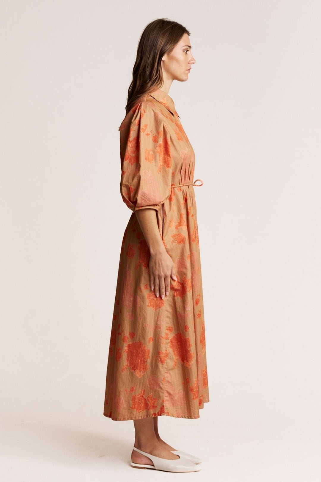 Woman wearing a long, patterned dress against a plain background