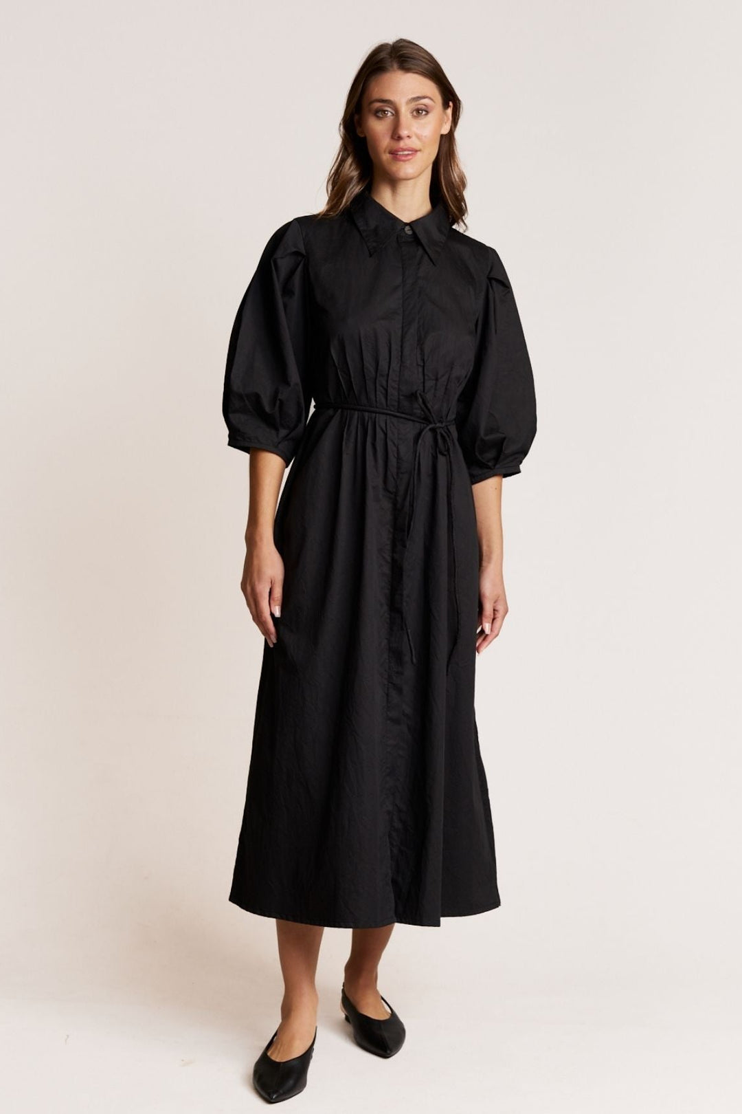 Woman wearing a black dress with puffed sleeves on a white background