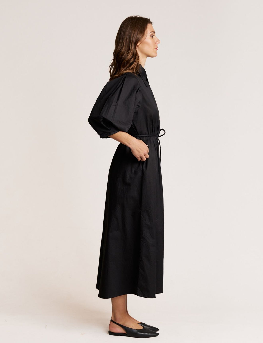 Woman wearing a black dress with a belt on a plain background