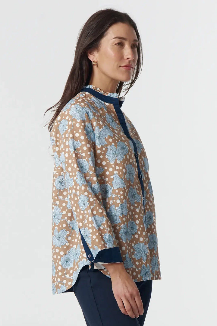 Woman wearing a patterned blouse and navy pants on a white background