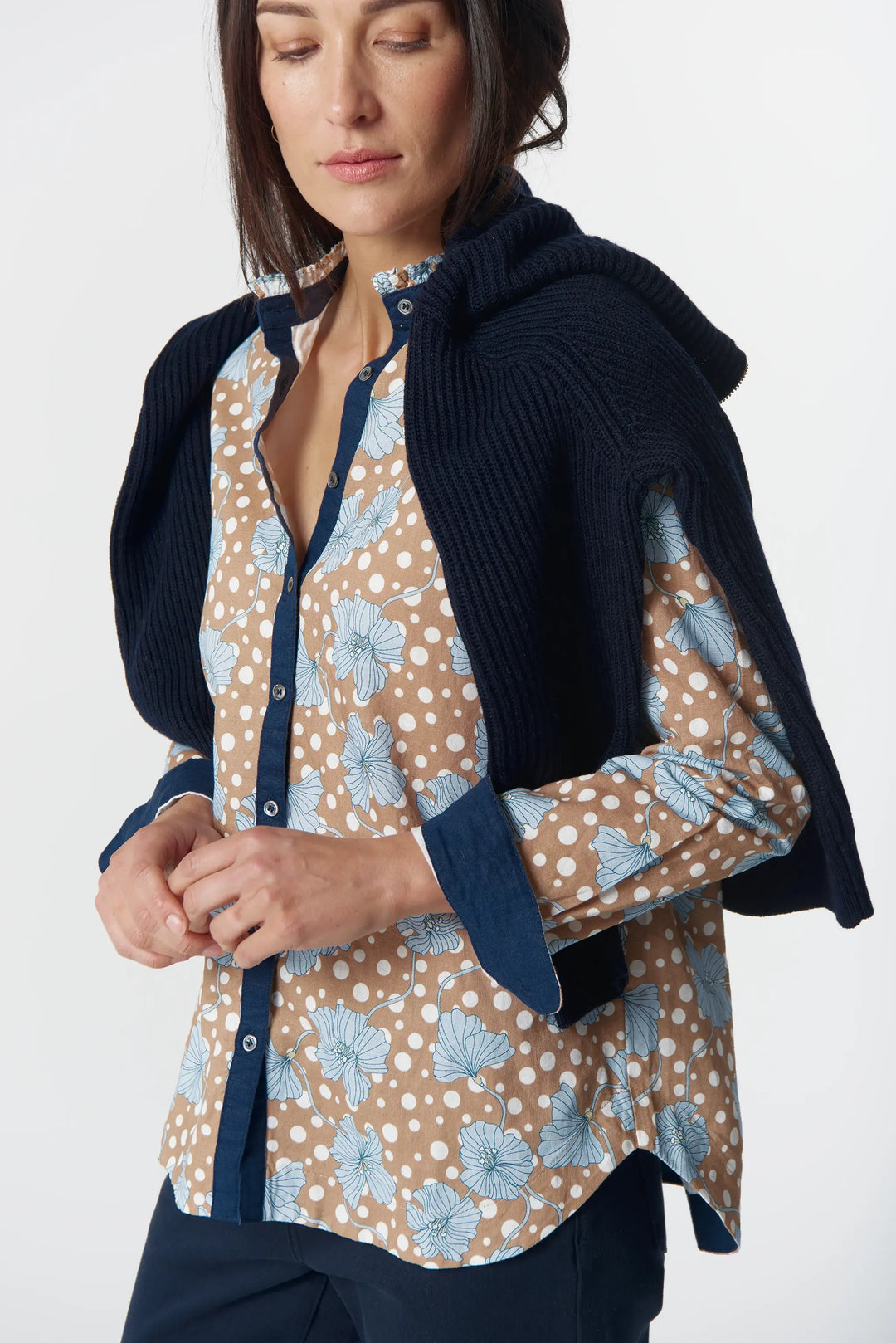 Woman wearing a navy cardigan over a patterned shirt on a white background