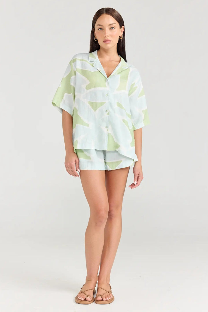 Woman wearing a light green and white patterned outfit on a white background