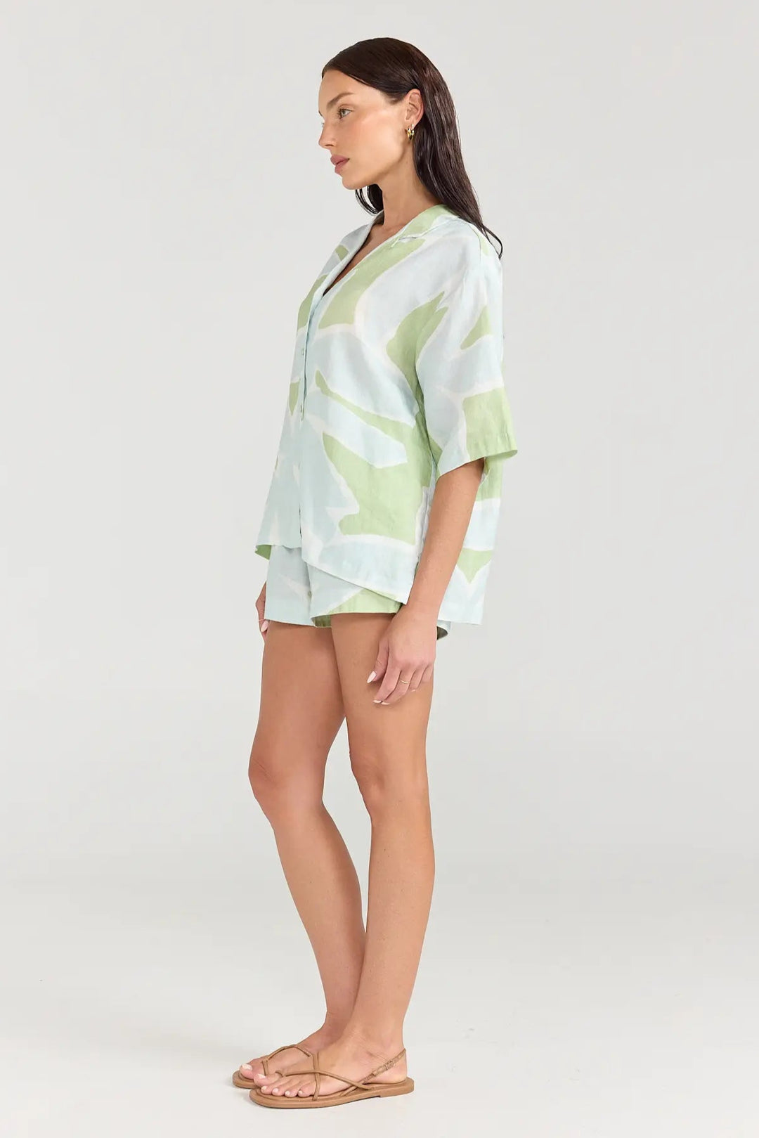 Woman wearing a light green and white patterned outfit on a white background