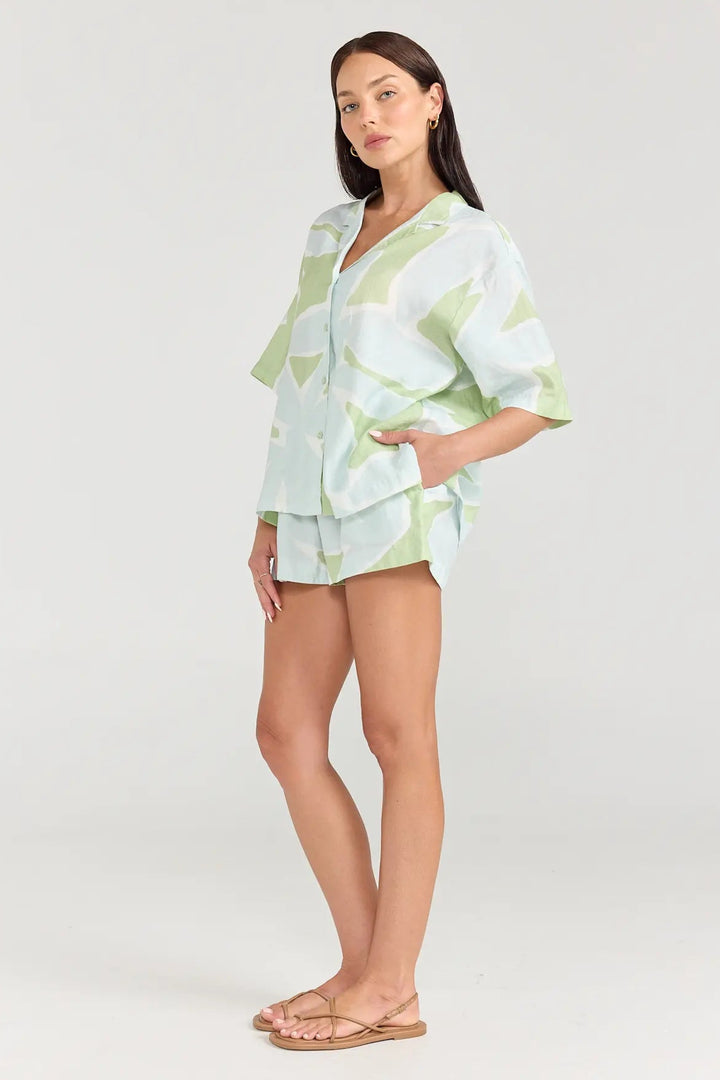 Woman wearing a light green tie-dye outfit on a white background