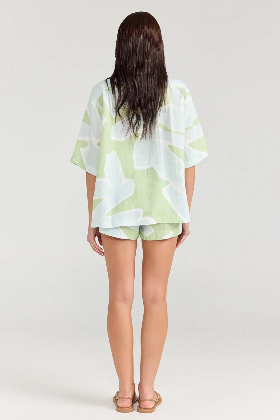 Person wearing a light green and white patterned outfit on a plain background