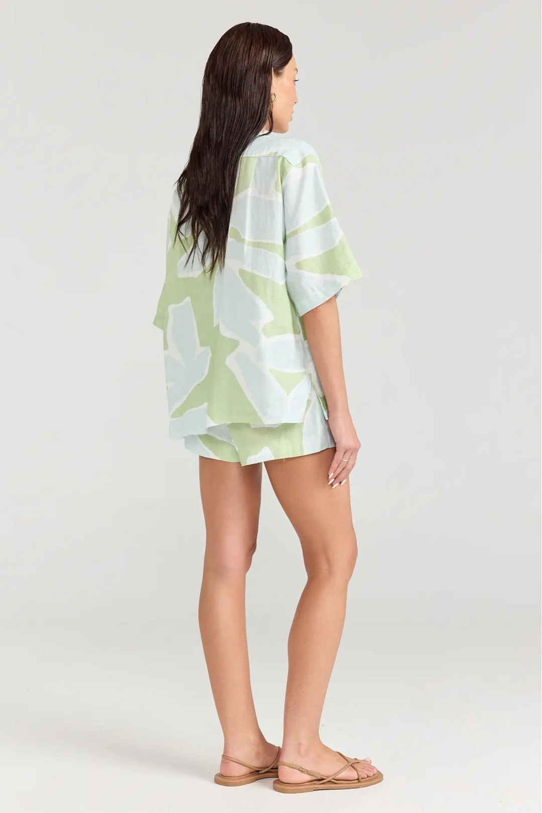 Woman wearing a light green and white patterned kimono-style top and shorts on a white background