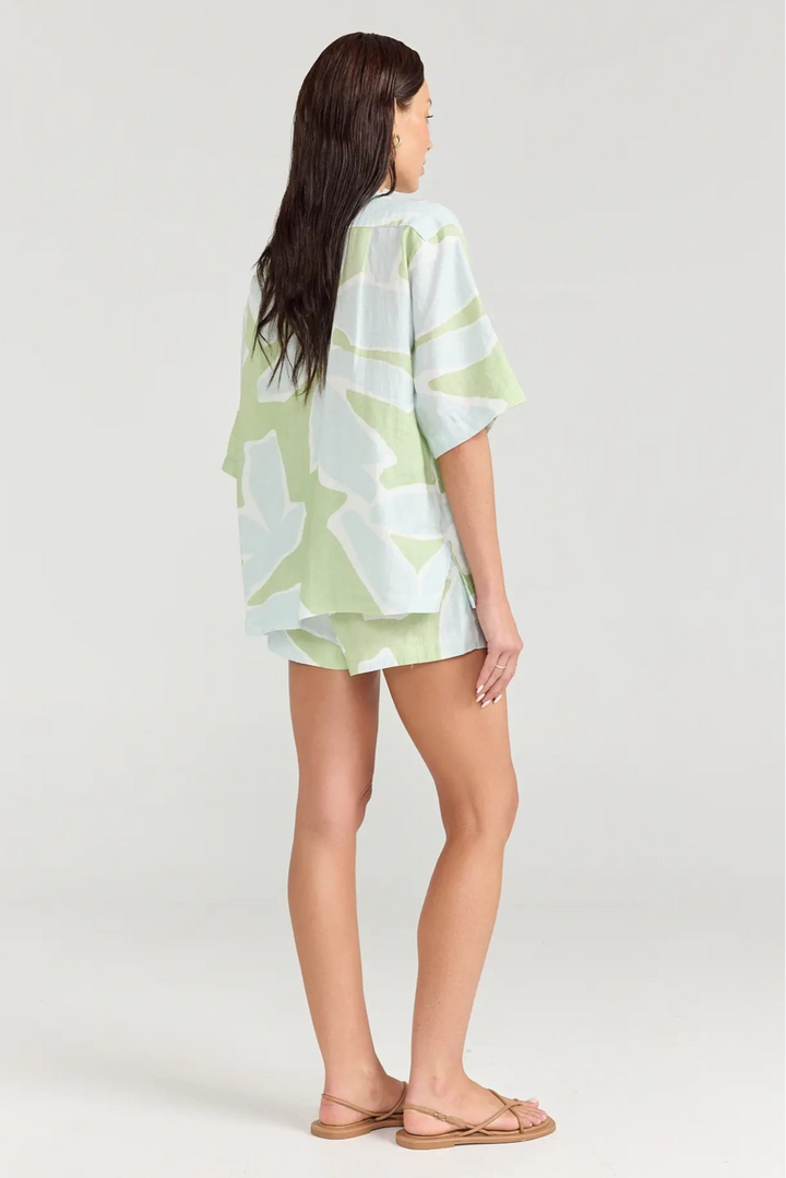 Woman wearing a light green and white patterned kimono-style top and shorts on a white background