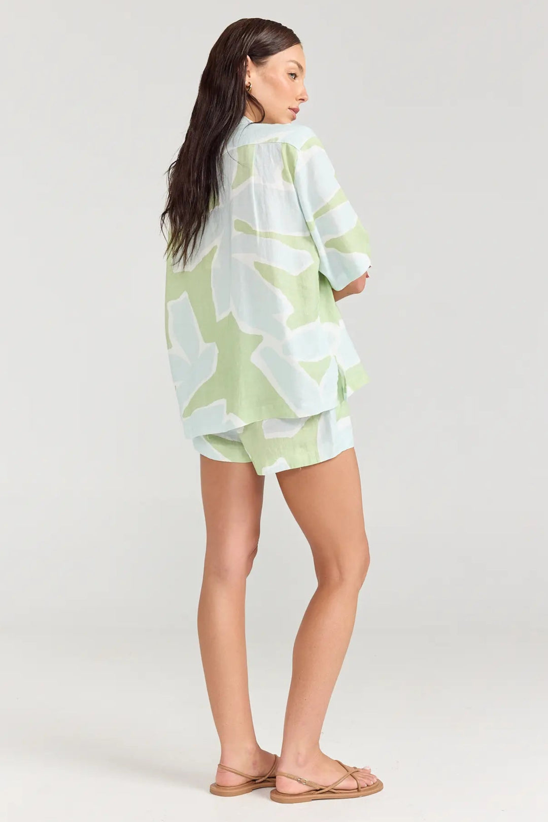 Woman wearing a light green and white patterned kimono-style garment on a plain background