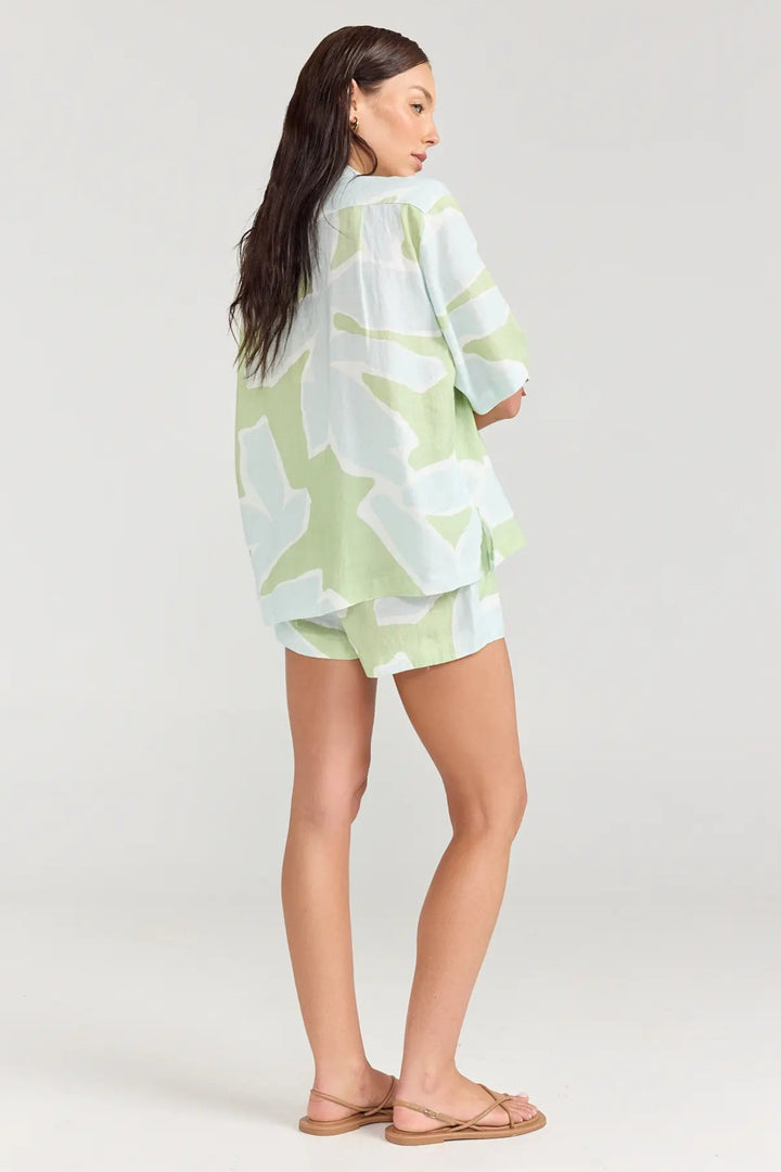 Woman wearing a light green and white patterned kimono-style garment on a plain background