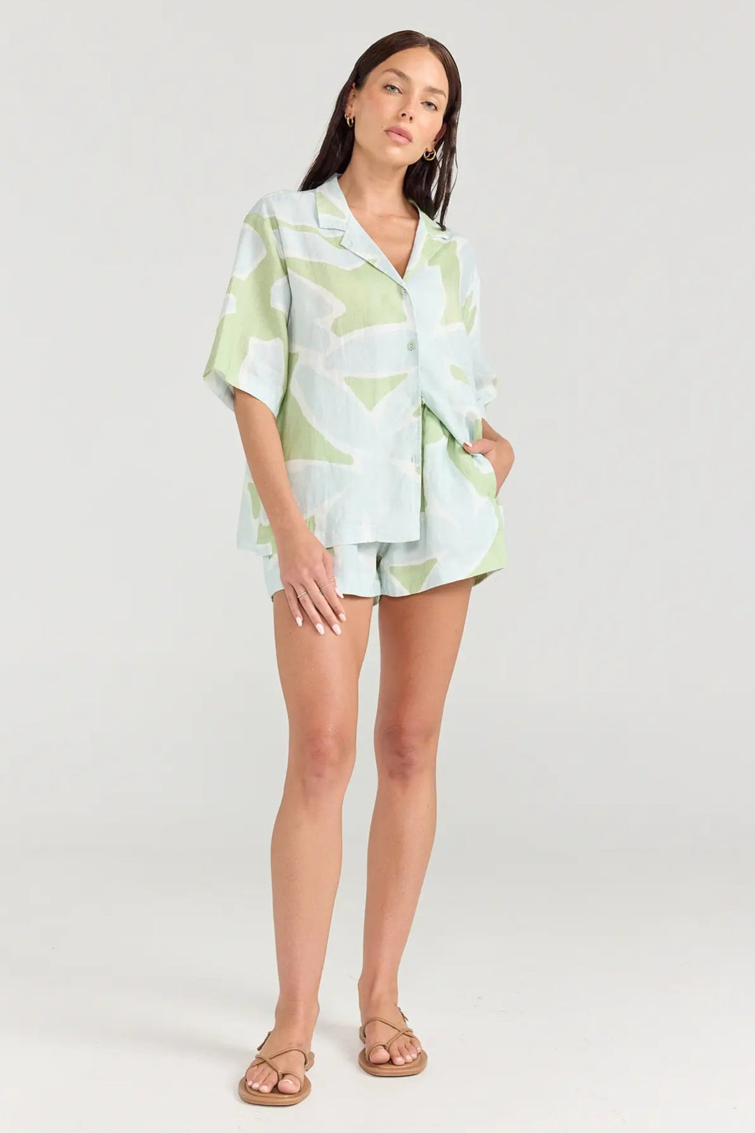 Woman wearing a light green and white patterned outfit on a white background