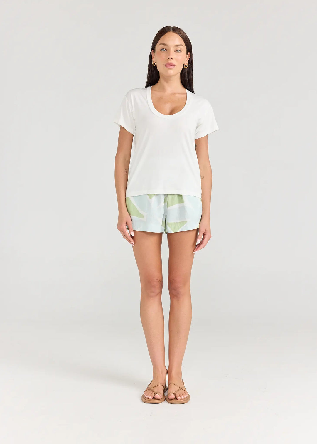 Woman wearing a white top and light green shorts on a white background