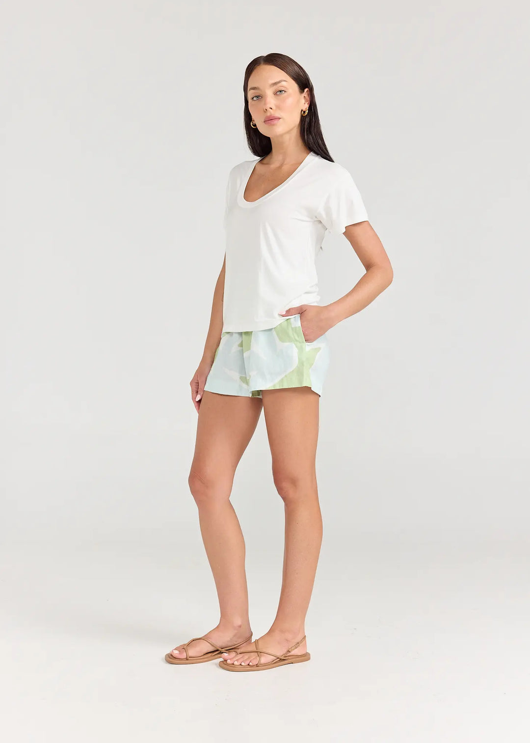 Woman wearing a white t-shirt and patterned shorts on a plain background