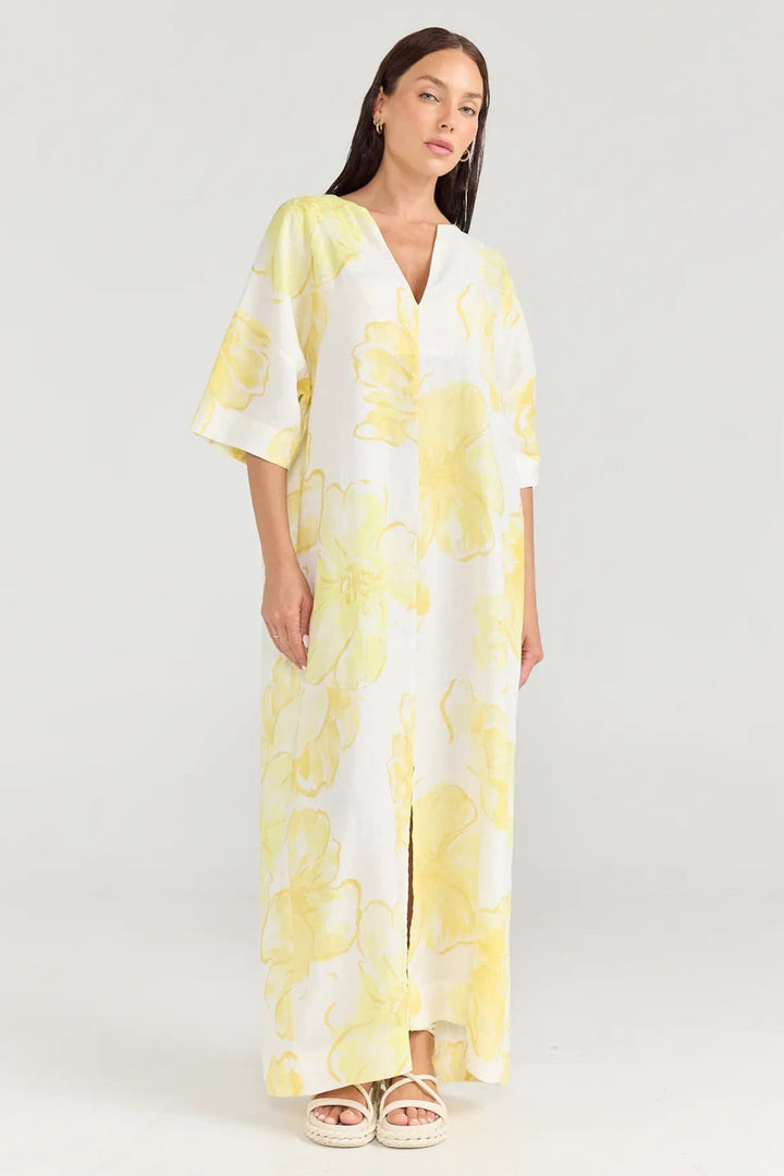 Woman wearing a yellow and white floral dress on a white background
