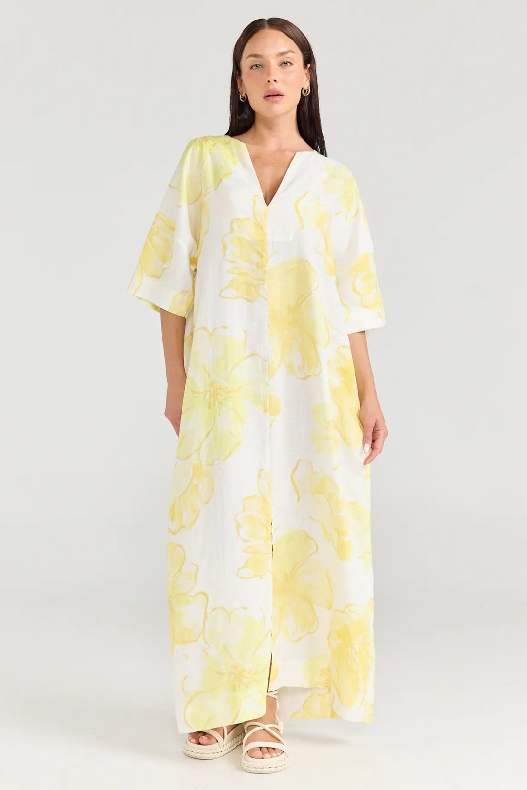 Woman wearing a yellow floral dress on a white background