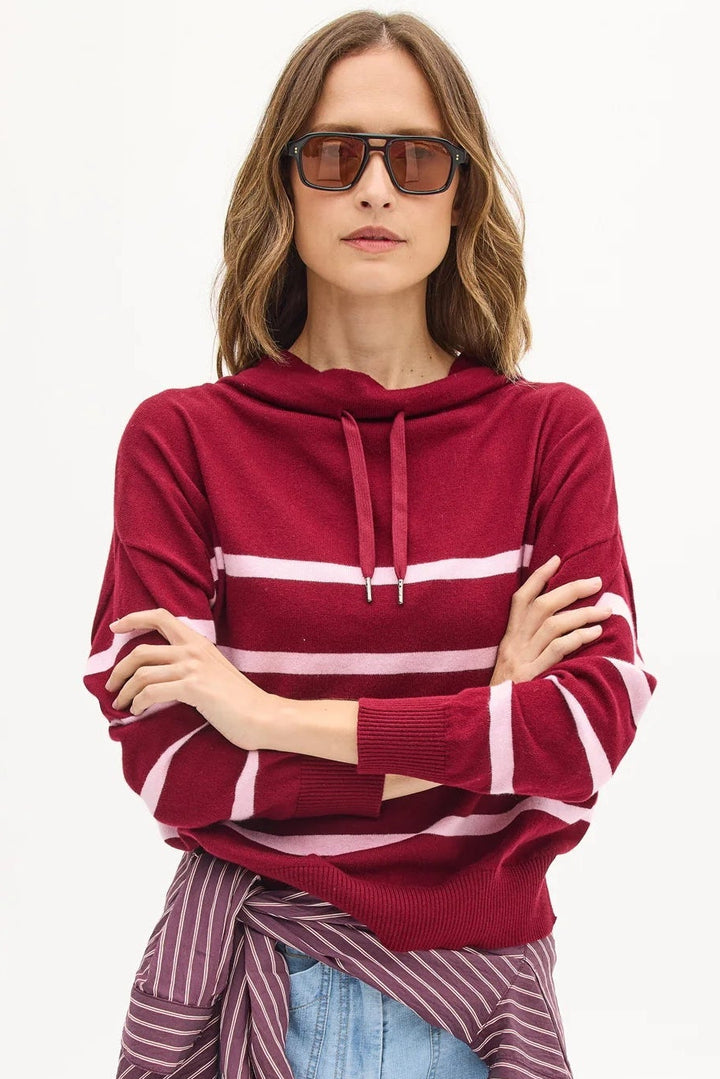 Woman wearing a red striped hoodie and blue jeans on a white background